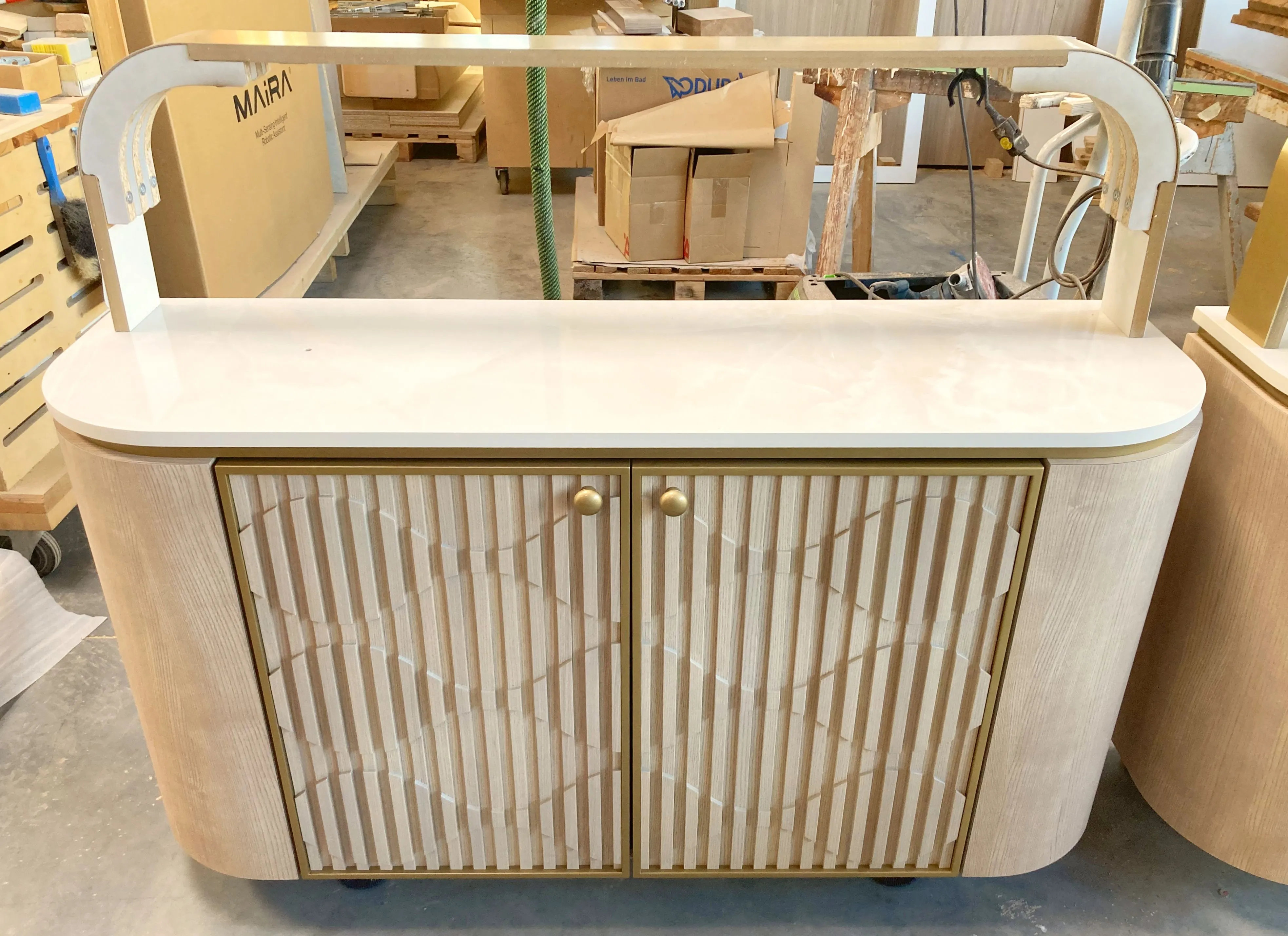 Helles Sideboard mit geriffelten Türen sowie Messing- und Natursteinelementen